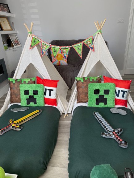 Two Minecraft teepees with creeper cushions, TNT pillows and inflatable swords. Bunting strung between the poles finishes the look, with fresh linen and a personal touch for every guest.