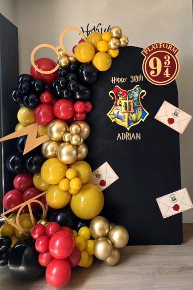 Harry Potter themed 30th birthday balloon and backdrop setup in Enfield, featuring black, red, gold and yellow balloons, Hogwarts crest, Platform 9¾ sign, and floating envelopes.