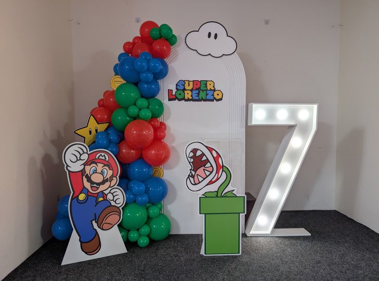 Colourful Super Mario-themed balloon arch with Mario, Piranha Plant, light-up number 7, and custom signage reading "Super Lorenzo".