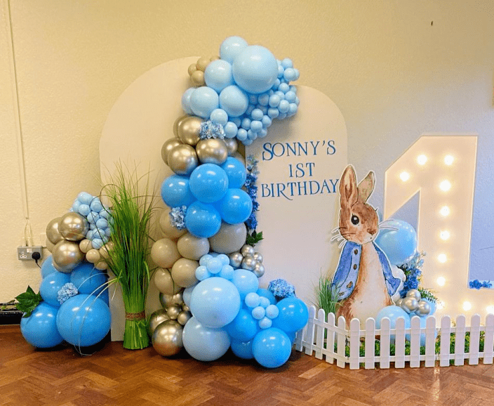 Peter Rabbit themed balloon backdrop in shades of blue, sand & gold.  Personalised with a birthday message and cut-out rabbit.
