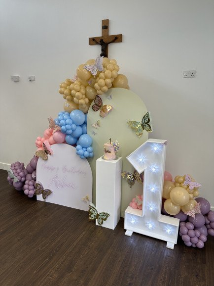 Butterfly and pastel themed 1st birthday balloon display