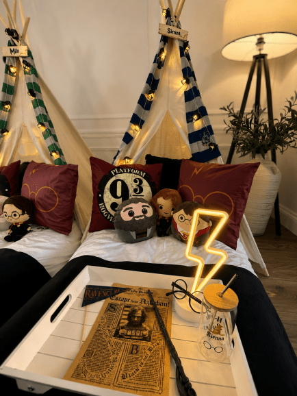 Twin teepee sleepover, styled in house colours with fairy lights, pillows, character plushes, wand, glasses and prop accessories.